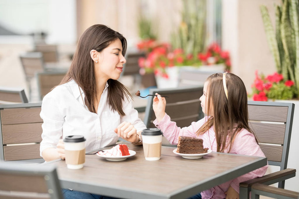 Hija alimentación pastel de su madre en la cafetería sobre fondo borroso
 - Foto, imagen