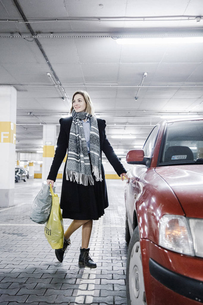 Une jeune femme dans un parking près d'une voiture. Fille après le shopping
. - Photo, image