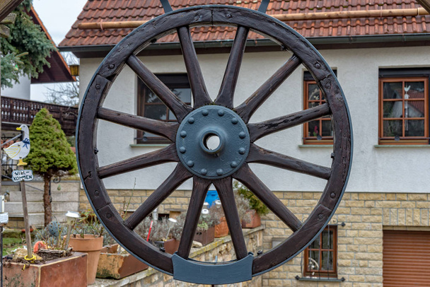 Wheel of a carriage is hanging on the gate for decoration - Photo, Image