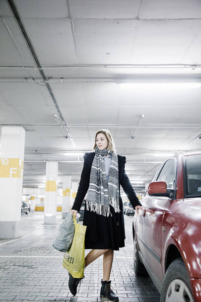 Young woman in a parking lot near a car. Girl after shopping. - Φωτογραφία, εικόνα