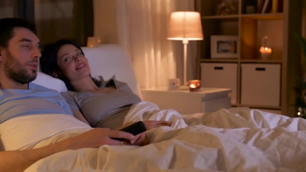 happy couple watching tv in bed at home - Séquence, vidéo