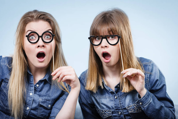 Two happy women holding fake eyeglasses on stick - Zdjęcie, obraz