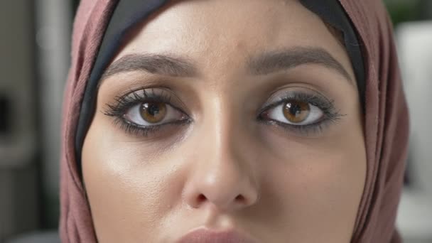 Young beautiful sad girl in pink hijab and looking at camera. Portrait, female eyes close up 60 fps - Felvétel, videó