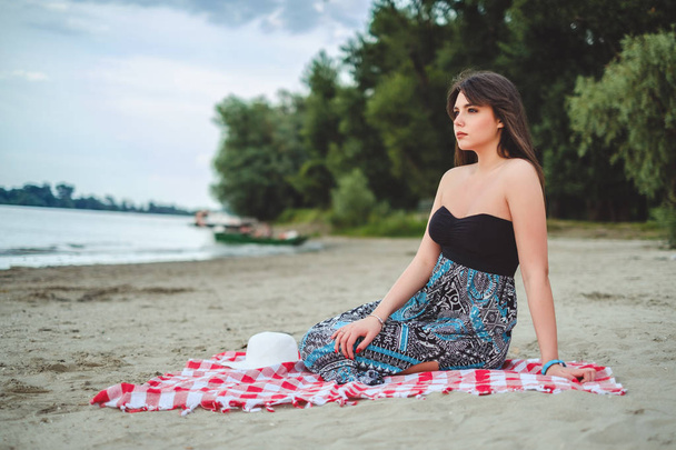 Ragazza seduta sulla spiaggia da sola e guardando lontano
 - Foto, immagini