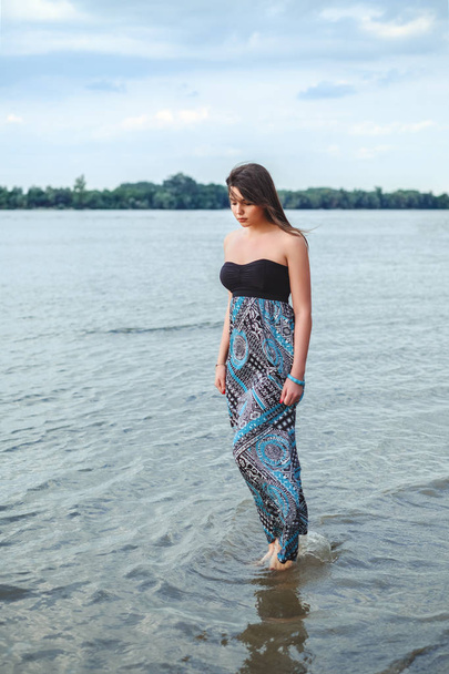 Ragazza che cammina da sola in acqua e tenendo il suo vestito
 - Foto, immagini