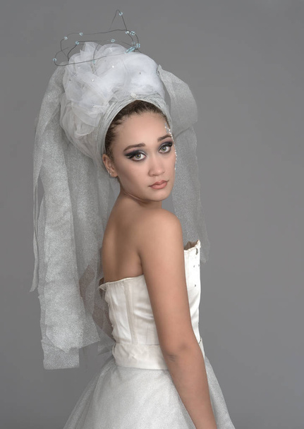 Young cute girl with green eyes posing in white dress and veil - Φωτογραφία, εικόνα