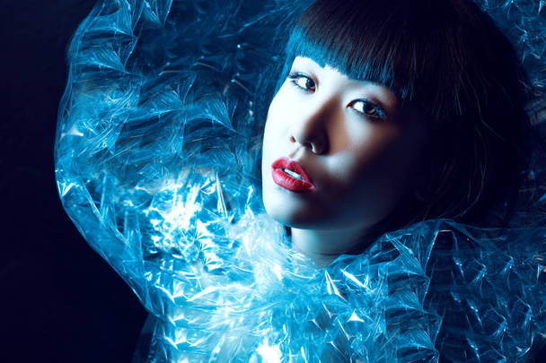 Close up portrait of gorgeous Asian model with beautiful make up and trendy haircut with fringe wearing fancy shining icy stand-up collar - 写真・画像