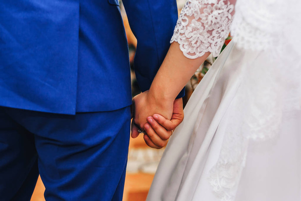 frisch verliebte Braut und Bräutigam halten bei Hochzeitszeremonie Händchen - Foto, Bild