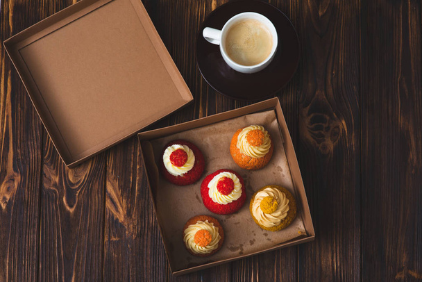 Box of colorful cupcakes and a cup of coffee - Zdjęcie, obraz