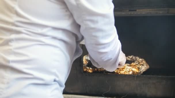 Koch räuchert das Fleisch auf dem Grill in der Großküche - Filmmaterial, Video