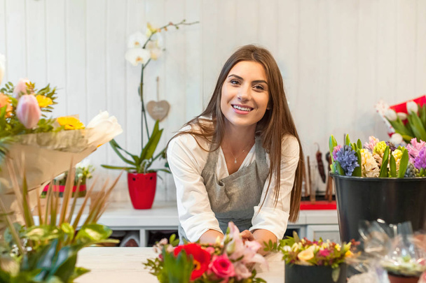 Mulher sorridente florista pequeno empresário dono de loja de flores, no balcão, olhando amigável para a câmera
. - Foto, Imagem