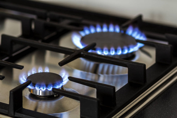 Brûlure de gaz naturel sur cuisinière à gaz de cuisine dans le noir. Panneau en acier avec brûleur à anneau de gaz sur fond noir, prise de vue rapprochée
 - Photo, image