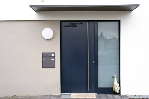 Entrada de casa moderna / La entrada de casa angular y moderna de un edificio residencial con una puerta de acero y un refugio
.                           - Foto, imagen