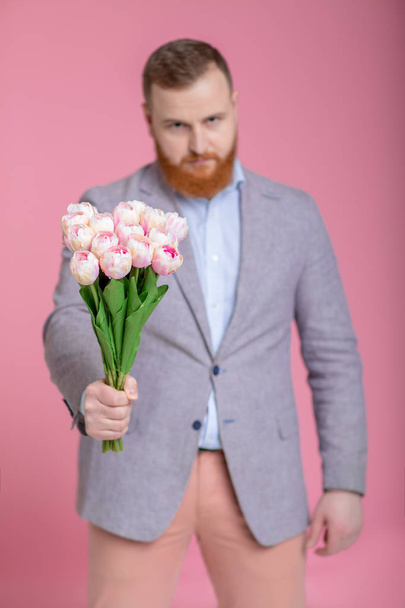 Handsome man holding bouquet of tulips - Фото, изображение