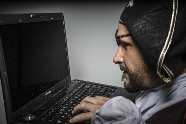 Homem de roupas de pirata, tentativa de hackear um laptop
 - Foto, Imagem