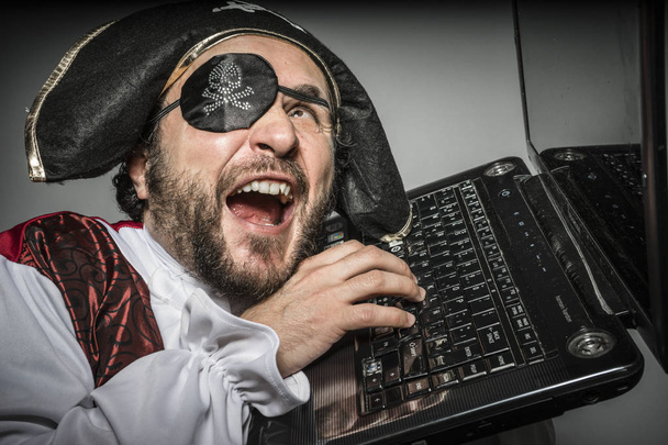 Man in pirate clothes, attempt to hack a laptop - Photo, image