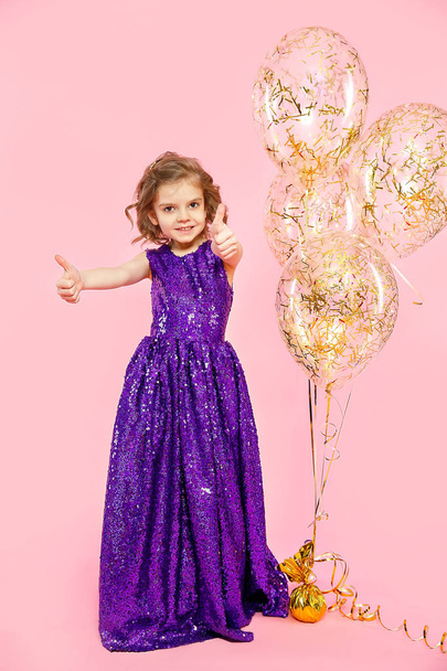 Girl showing thumbs up at festive balloons - Valokuva, kuva