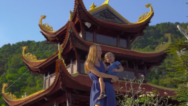 Steadycam schot van een jonge vrouw en haar zoon een budhist tempel Ho Quoc pagode bezoeken op het eiland Phu Quoc, Vietnam - Video