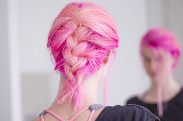 Ροζ μαλλιά γυναίκα με μια πλεξούδα που βλέπουν στον καθρέφτη - Φωτογραφία, εικόνα