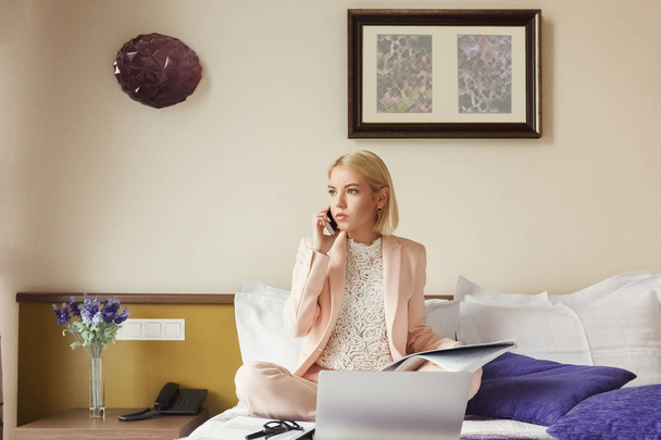Бизнесмен, сидящая на кровати и пользующаяся ноутбуком
 - Фото, изображение
