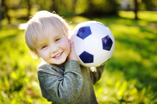 Little boy having fun playing a soccer game on sunny summer day - Foto, immagini