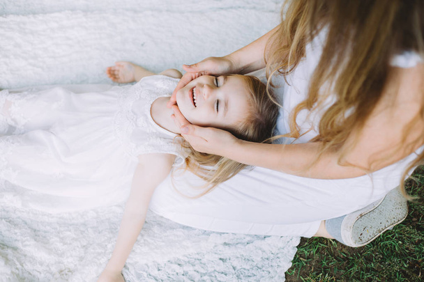 портрет милої маленької усміхненої дівчинки, що лежить на колінах своєї матері
  - Фото, зображення