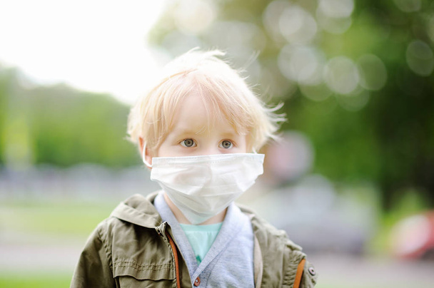 Little boy wearing medical face mask as protection against infectious diseases - Fotó, kép