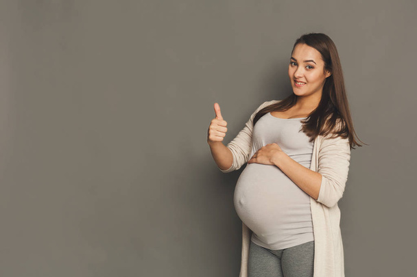 Donna incinta con pollice in su gesto
 - Foto, immagini