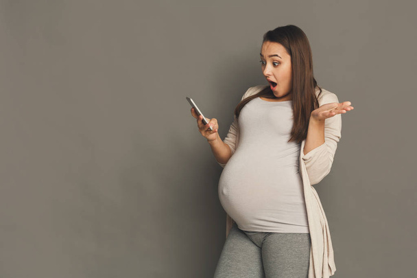 Surprised pregnant woman using smartphone - Photo, Image