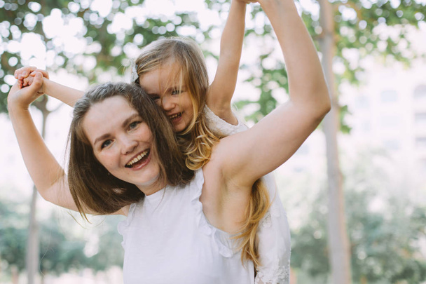 美しい若い女性彼女の小さな娘は楽しいことをやって夏の公園でピギーバック - 写真・画像