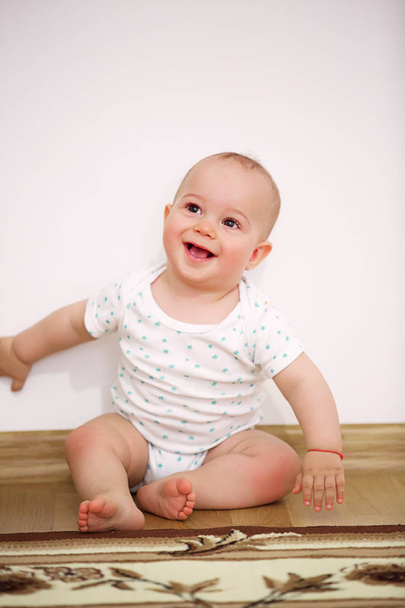 Happy baby boy sitting on floor at children's room - Fotó, kép