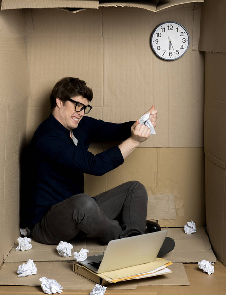 Trabajador enojado está rasgando papel dentro de una pequeña caja de cartón
 - Foto, Imagen