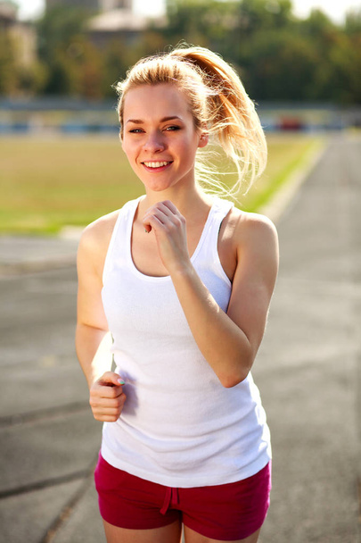 Happy girl jogging at sport stadium healthy lifestyle outdoors - Foto, afbeelding