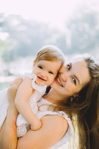 bela jovem sorrindo mulher abraçando sua filhinha no parque de verão
 - Foto, Imagem