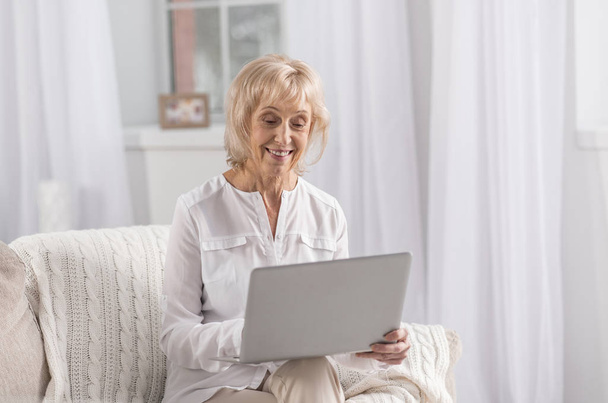 Cheerful mature woman searching web - Foto, imagen