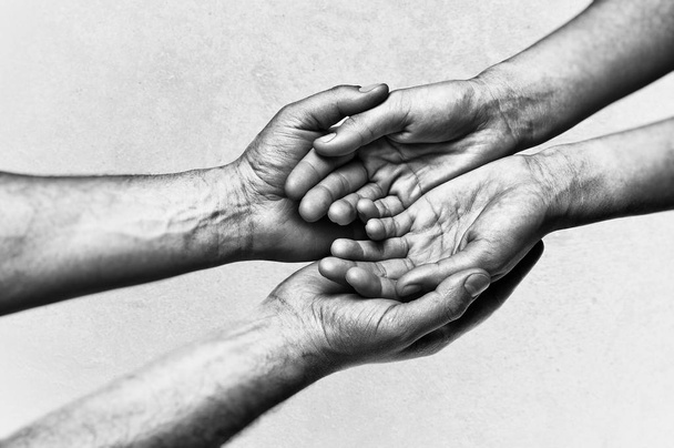 Man's hands holding female palms on scratched background. Black and white image. - Photo, Image