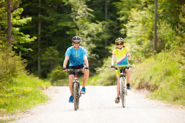 ACTIVO Jovem casal de bicicleta em uma estrada florestal na montanha em uma spr
 - Foto, Imagem