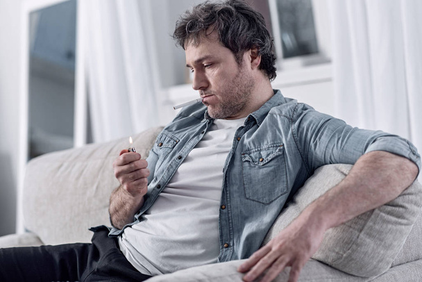 Evde oturan ve bir sigara aydınlatma şanssız adam - Fotoğraf, Görsel