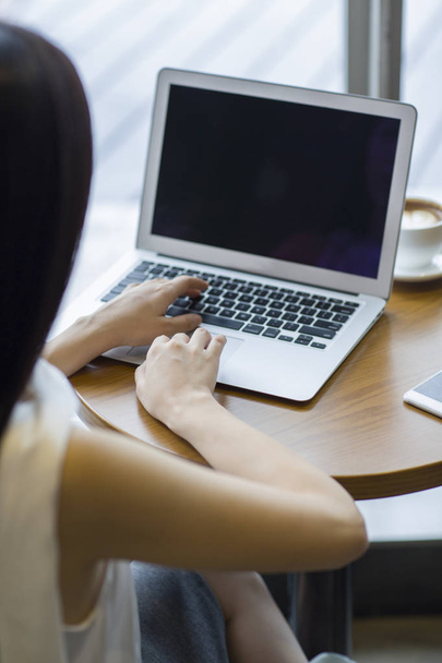Femme travaillant avec un ordinateur portable dans un café, vue arrière
 - Photo, image