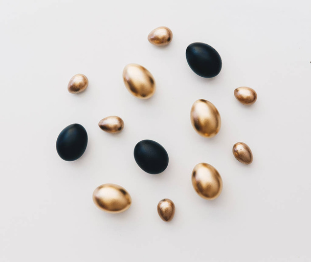 Flat lay black and gold eggs. Minimal easter background  - Фото, изображение