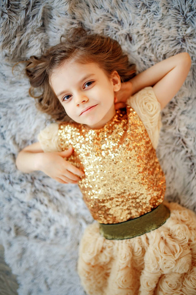Girl in golden dress on fur - Foto, Imagen