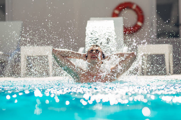 Giovane uomo godendo piscina spa giorno in vacanza rilassante resort.Campered uomo, metropolitana sessuale, la cura per il corpo e il benessere.Hydro massaggio per il dolore al collo.
. - Foto, immagini