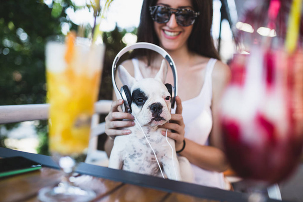 Cute white french bulldog puppy enjoying in owner's lap and listening to music - Zdjęcie, obraz