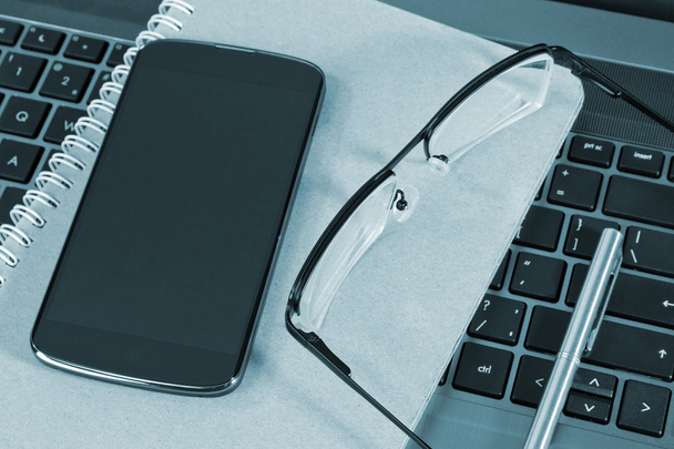 Мобільний телефон і окуляри на ноутбуці
 - Фото, зображення