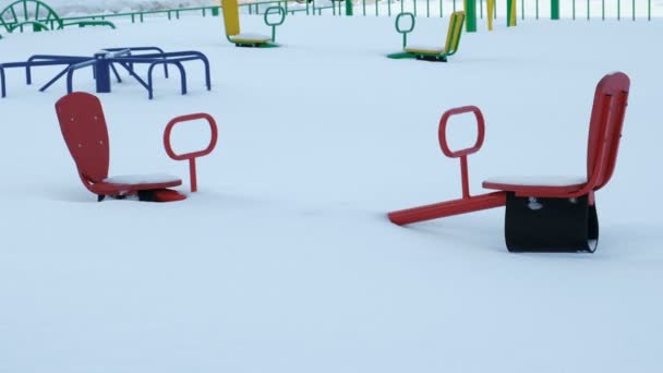Kinderspielplatz mit Wippe und Karussells im Schnee im Winter. die Kamera ist statisch. - Filmmaterial, Video