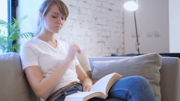Penisve kobieta czytanie książki siedząc na kanapie - Materiał filmowy, wideo