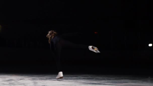 Un patineur professionnel en costume noir effectue la rotation debout sur une jambe en position avalée sur la glace en patins à glace dans un tir au ralenti. De la position debout, il tombe dans une séance
 - Séquence, vidéo