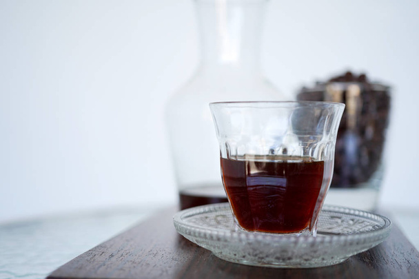 Coffee in a transparent cup on a wooden plank. In the background is a jar of coffee aroma and coffee beans. Close-up with copy space - Photo, Image