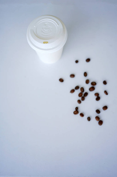 Jednorazowego kubka do kawy z ziaren kawy, stoi się na białe płytki. Widok z góry z miejsca kopii - Zdjęcie, obraz