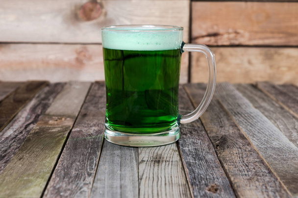 Single mug of green beer on wooden background - Фото, изображение